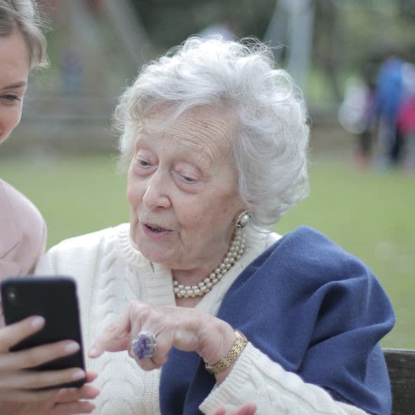 An older woman with white hair using an app on a smartphone